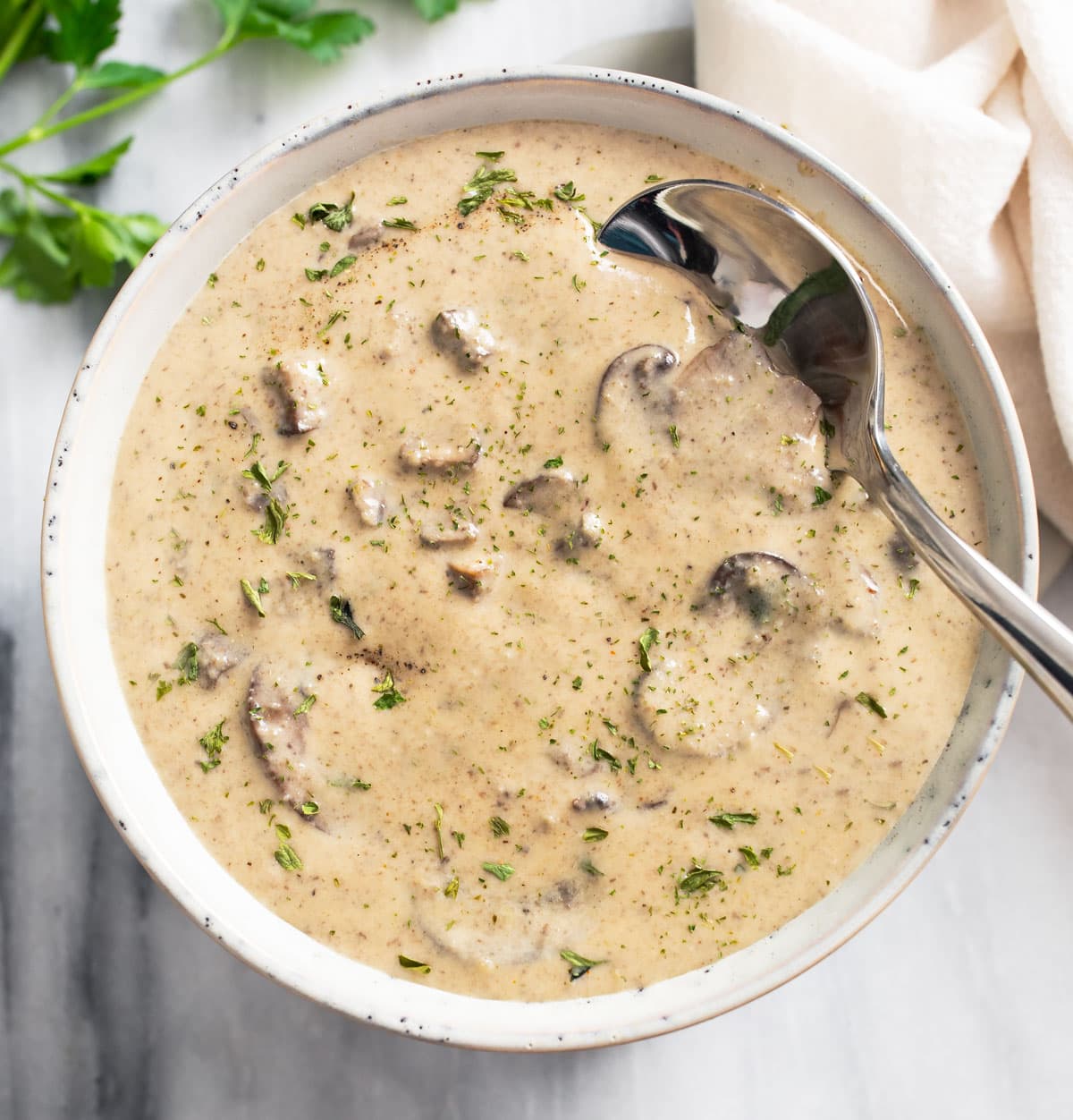 A bowl of Cream of Mushroom Soup with a spoon on the side.