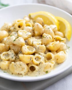 Garlic Butter Pasta on a white plate with lemon slices in the background.