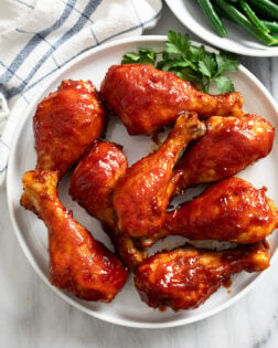 Overhead view of BBQ Chicken on a white plate with parsley on the side.