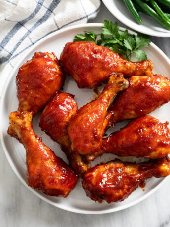 Overhead view of BBQ Chicken on a white plate with parsley on the side.