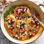 A skillet of Balsamic Chicken with berries and feta on top with fresh rosemary on the side.