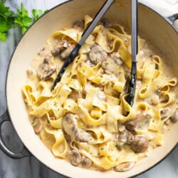 Truffle Pasta with a creamy mushrooms sauce and pappardelle pasta in a skillet with tongs on the side.