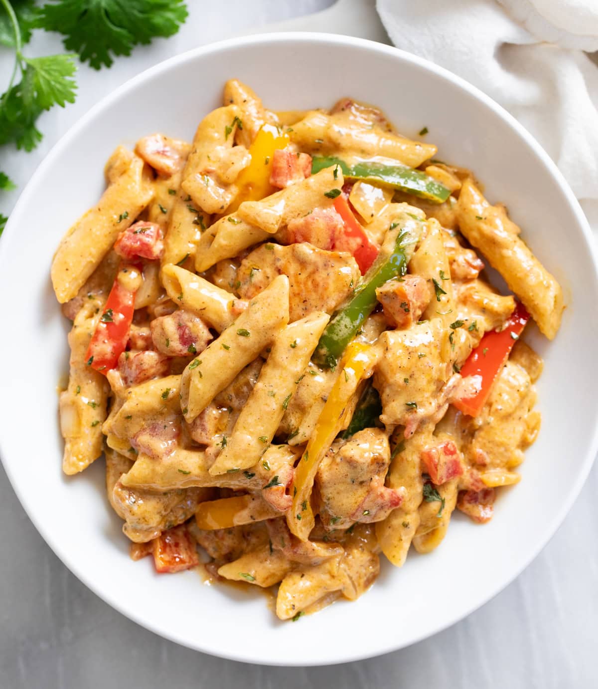 Chicken Fajita Pasta in a white bowl with bell peppers, sauce, and chicken.