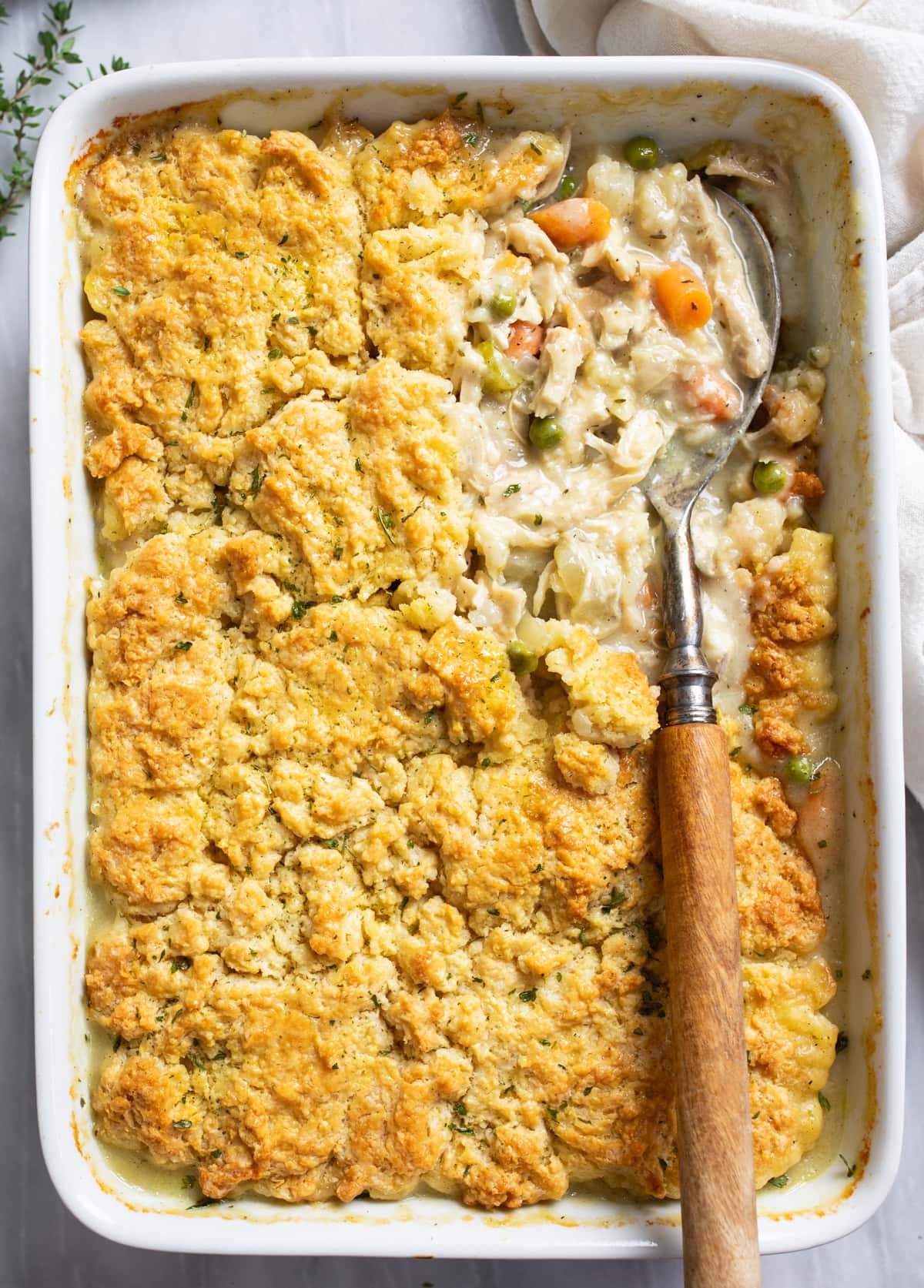 Chicken Pot Pie Casserole in a white casserole dish with a serving spoon on the side.