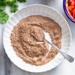 Homemade Taco Seasoning in a white bowl with a spoon on the side.
