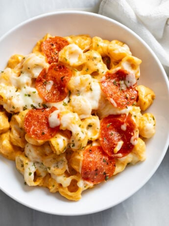 Pizza Mac and Cheese with mozzarella and pepperoni on top in a white bowl.
