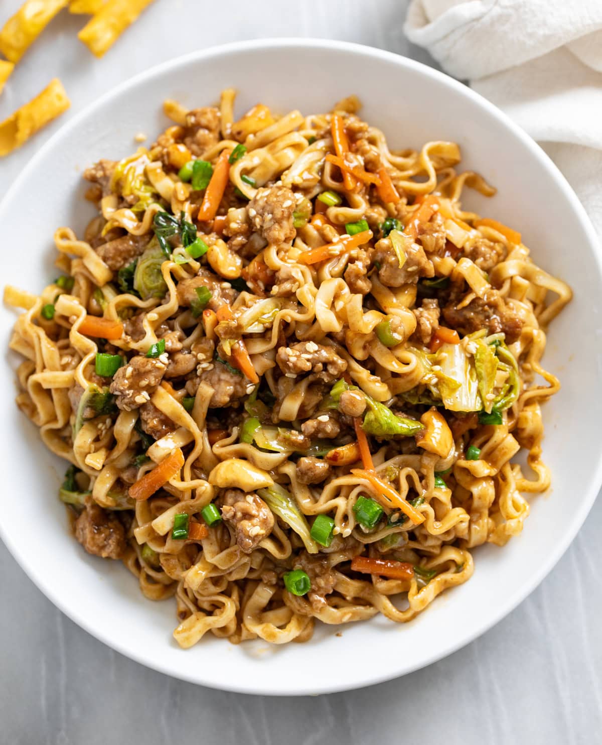 Pork Noodles in a white bowl with green onions on top and Chinese noodles on the side.