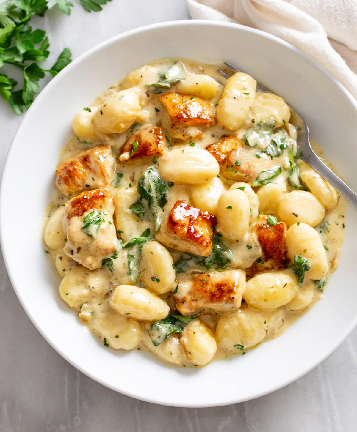 Creamy Chicken Gnocchi in a white serving bowl with a fork on the side.