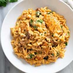 Marry Me Chicken Orzo in a creamy tomato sauce with sun-dried tomatoes and spinach in a white bowl.