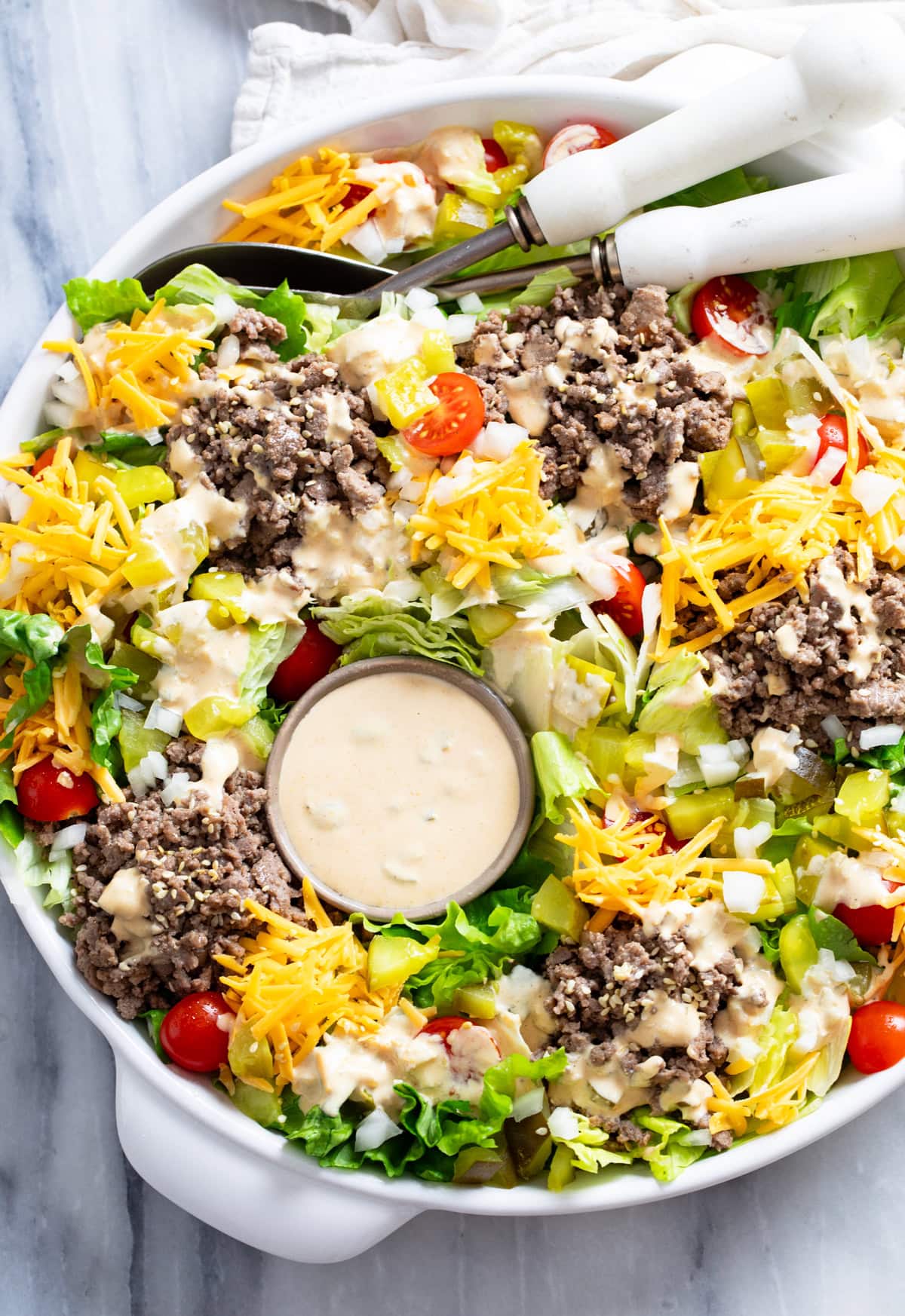 Big Mac Salad with big mac salad dressing, lettuce, ground beef, cheese, pickles, onions, and tomatoes in a white bowl.