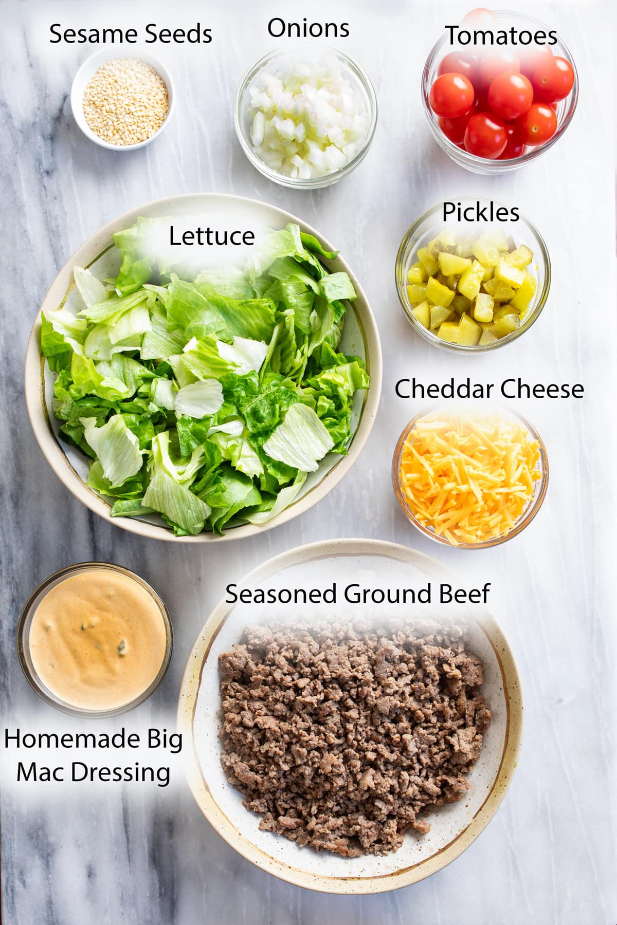 Labeled ingredients on a white surface for making Big Mac Salad.